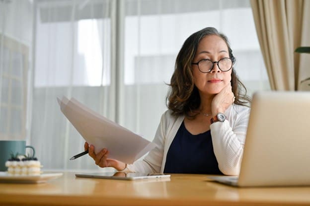 Senior Living PPC business woman looking at her laptop while holding some printed documents