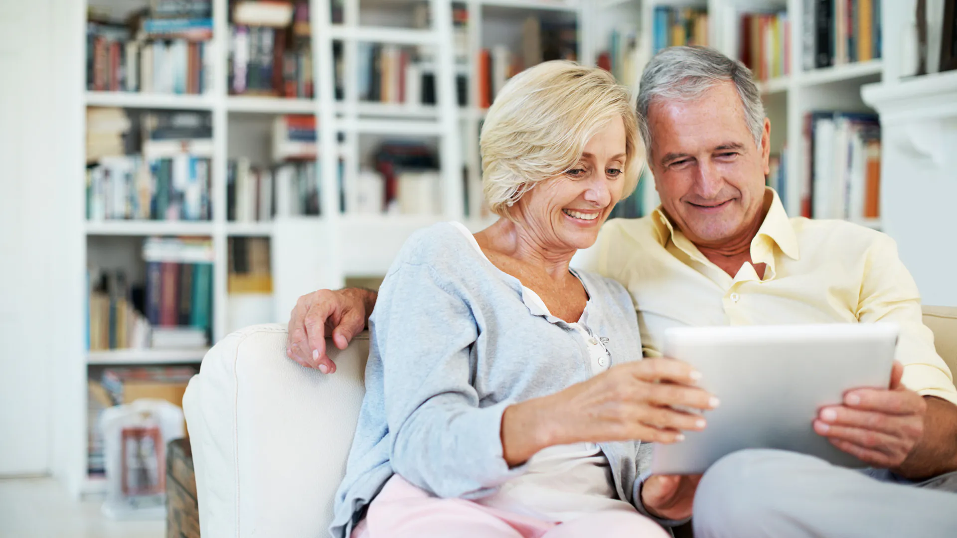 A senior couple reading an ebook together in their study at home