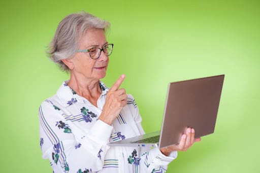 a senior woman thoughtfully reflects on the senior living website design she sees on the screen