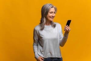 a senior woman looking at her phone reading a text utilizing our top SMS text strategies for senior living