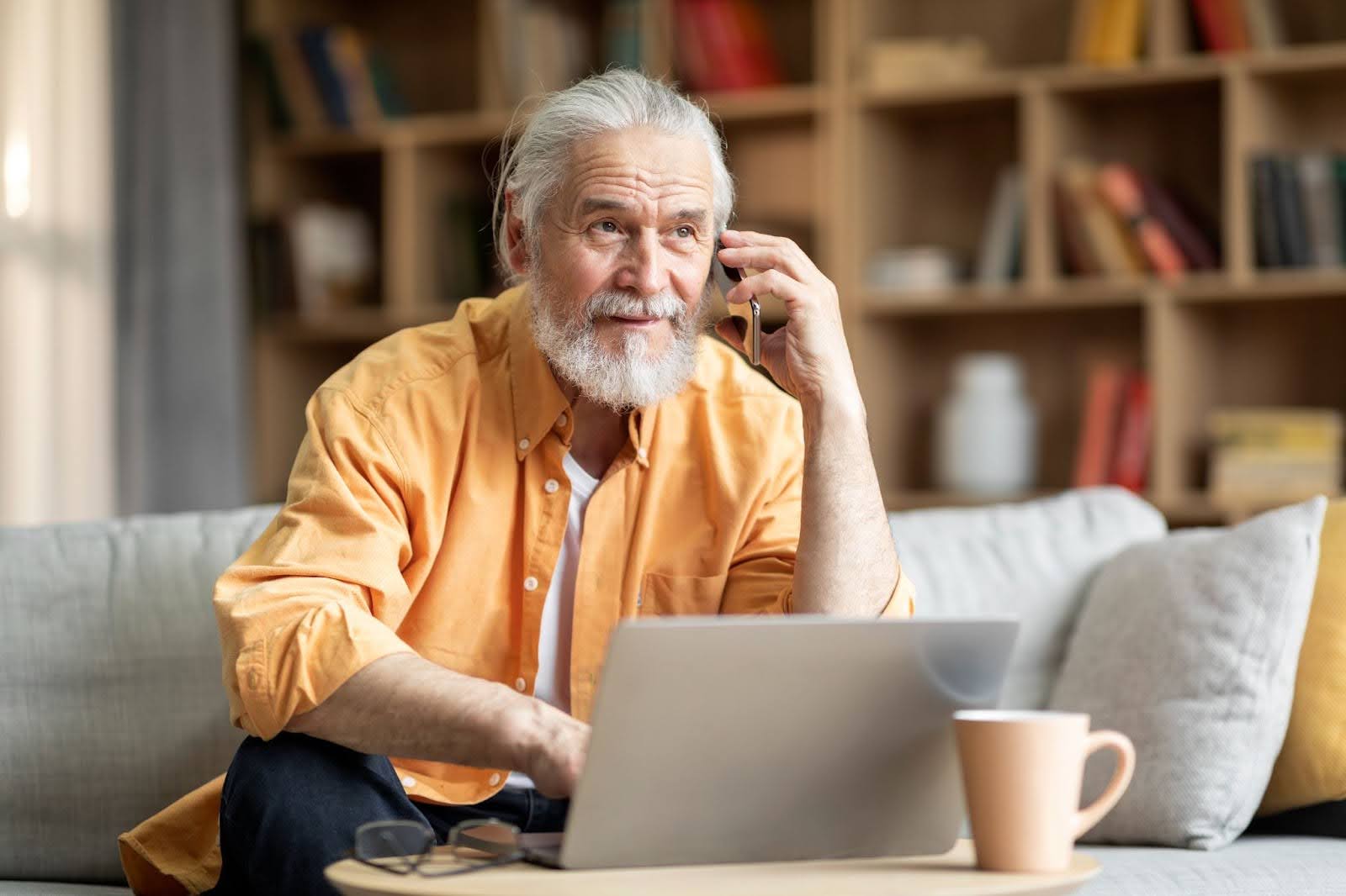 A senior man on his laptop and talking on the phone discussing 7 strategies that drive clicks for email marketing in senior living.