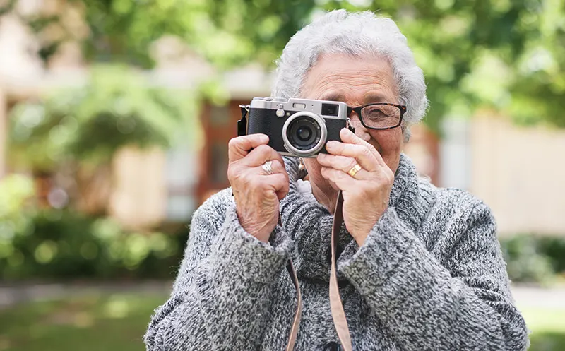 A women holding up a camera to her eye to take a photo.