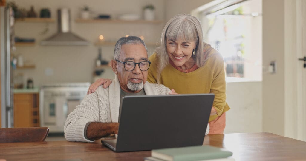 senior couple at home enjoying social media content on laptop