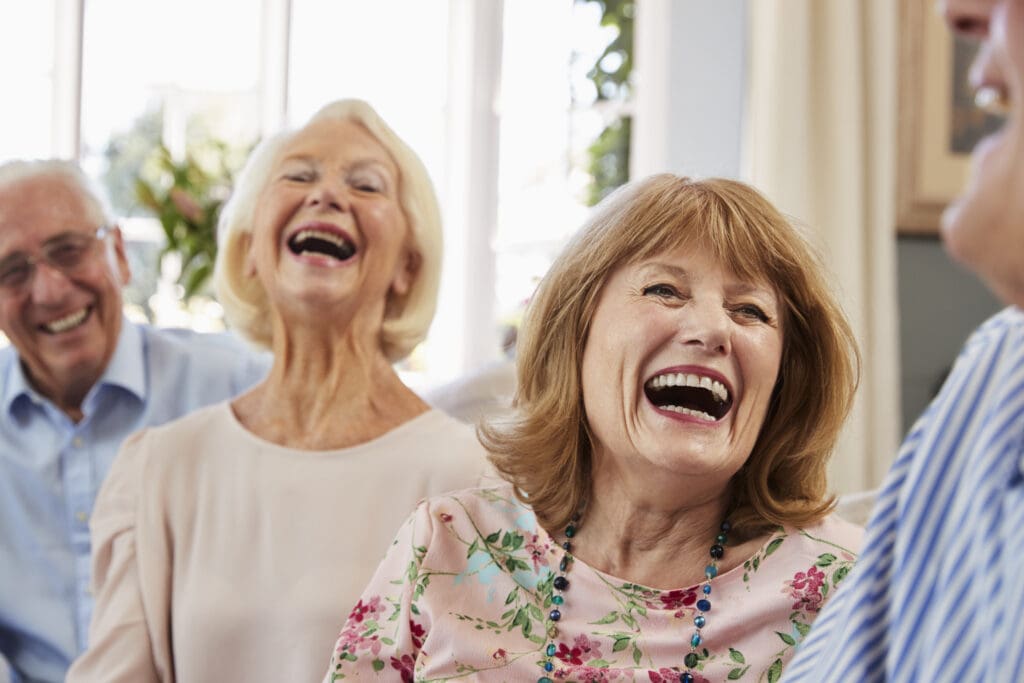 two senior couples, laughing, enjoy their senior living community