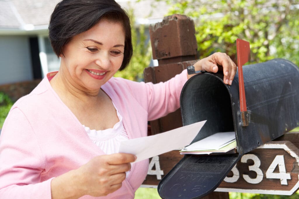 smiling senior hispanic woman reads direct mail from a senior living community