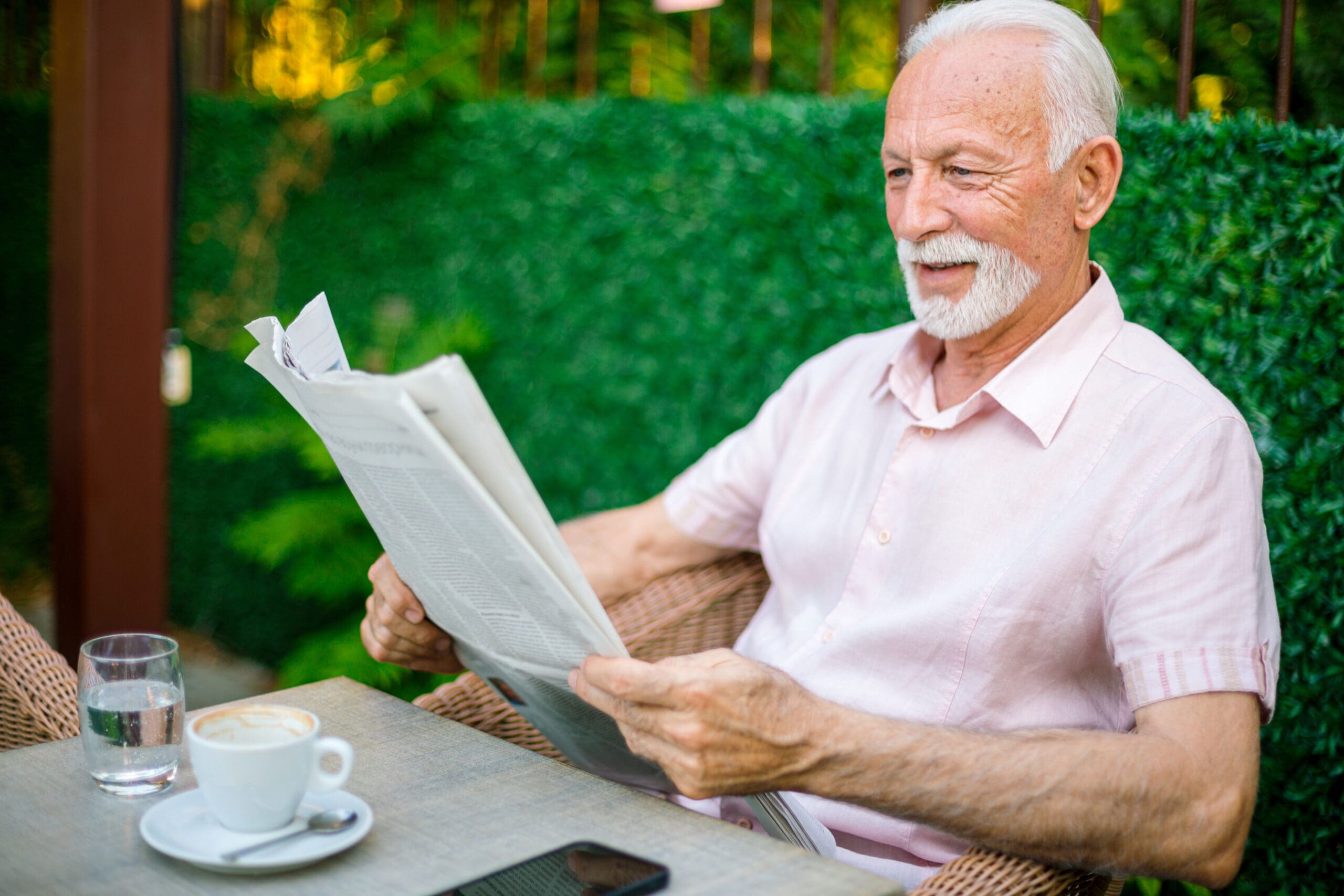 Senior man enjoying newspaper and coffee at outdoor cafe