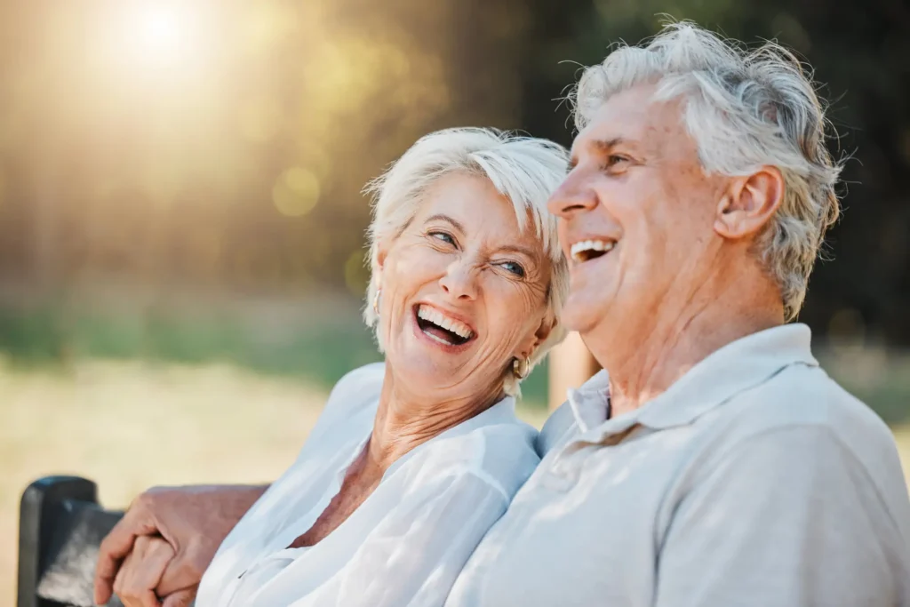 Senior couple, laughing on a park bench