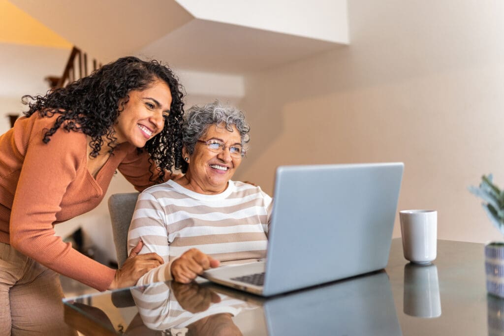 Senior woman using laptop and talking to daughter at home