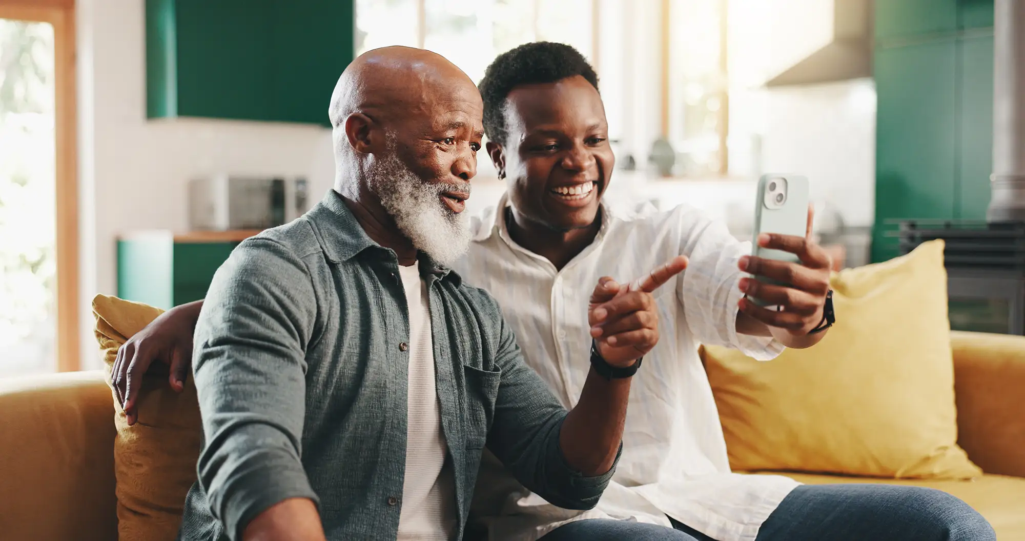 Senior man taking a selfie with a mobile phone alongside his adult son.