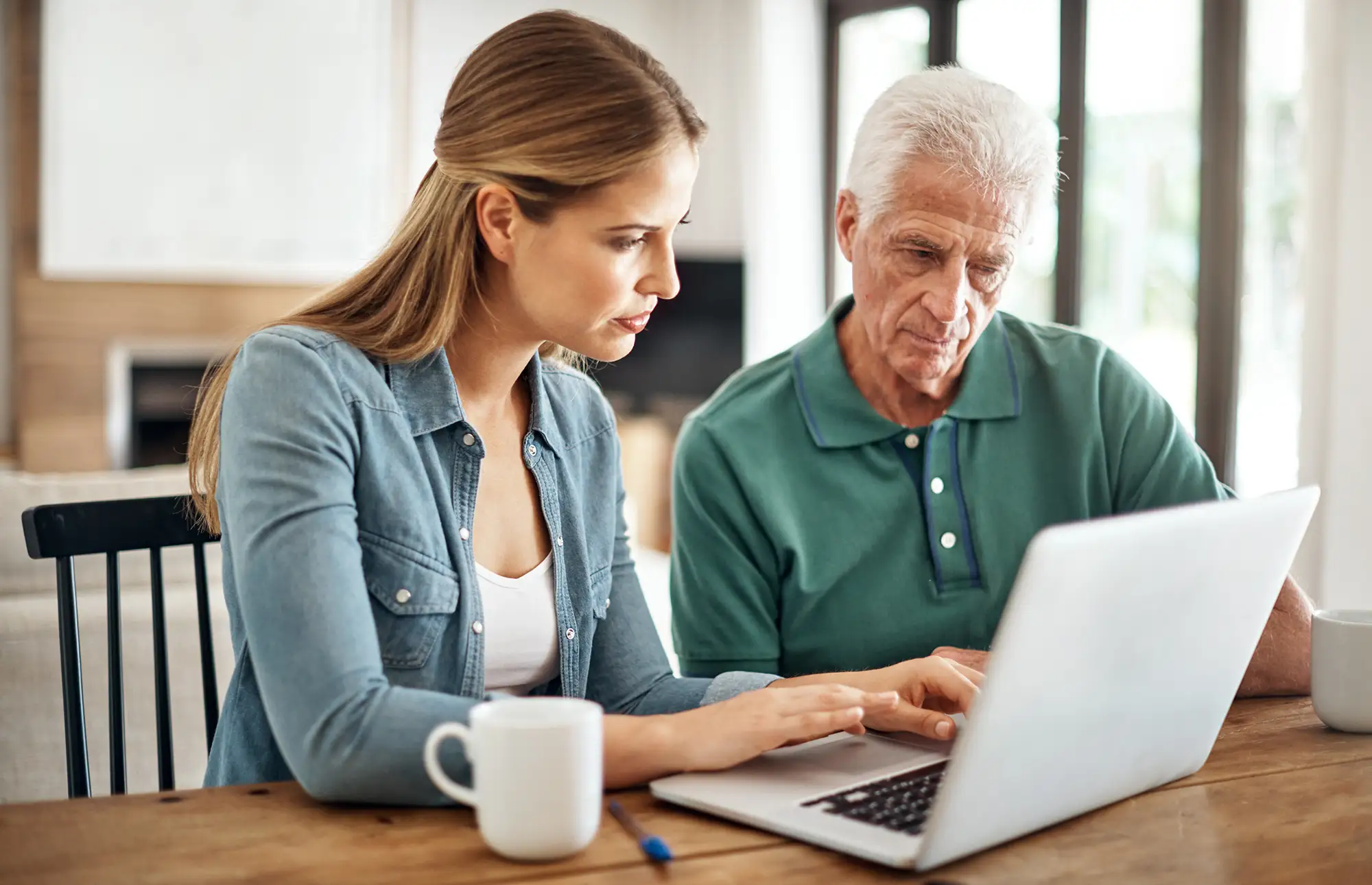 Senior man searching for senior living facilities near him with the help of his adult daughter.